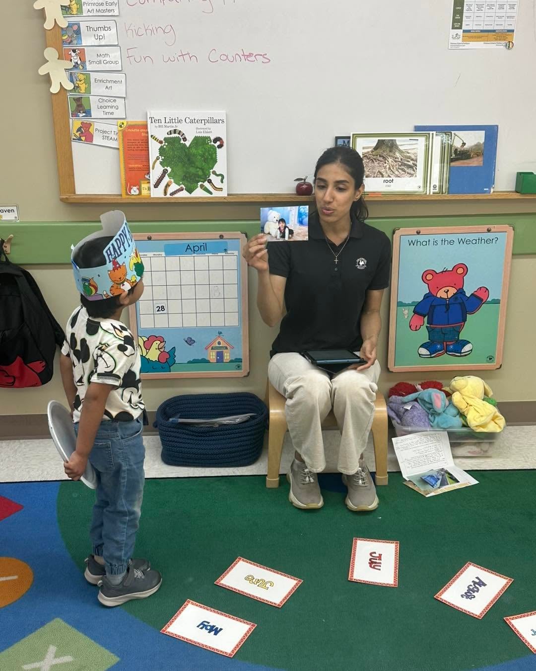 Preschool teacher leading an interactive circle time lesson with a student, encouraging language development, listening skills, and classroom participation at Primrose School.