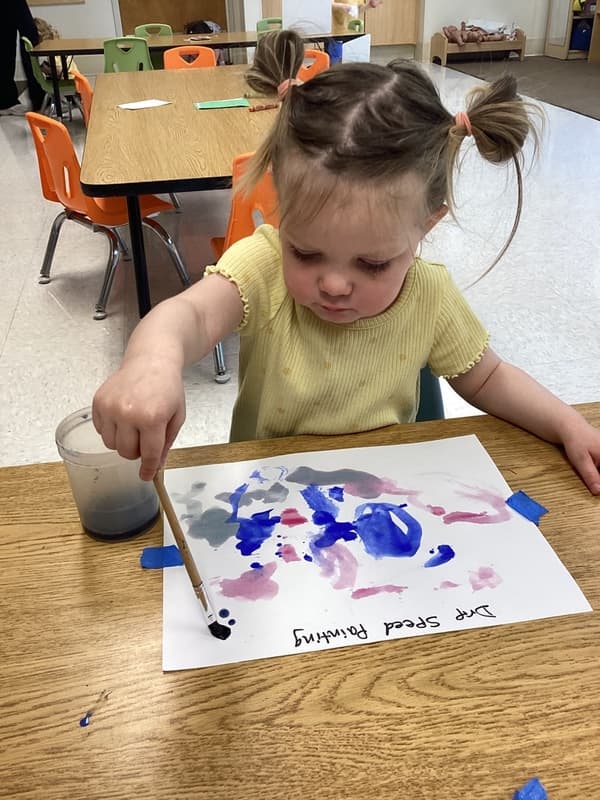 A little girl painting with a paintbrush