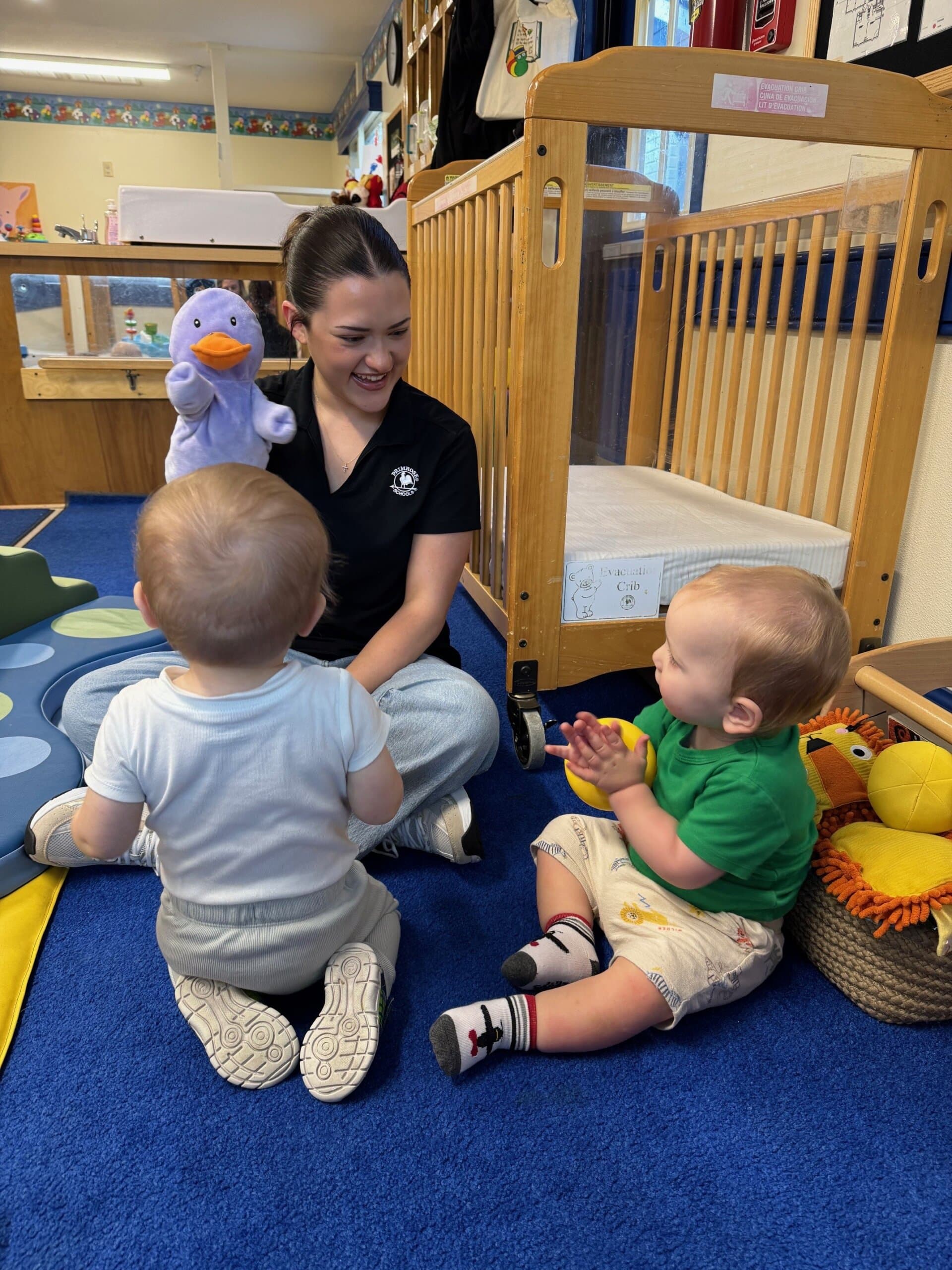 Teacher smiling at young students while using a hand puppet during an interactive classroom activity, encouraging engagement and imaginative play