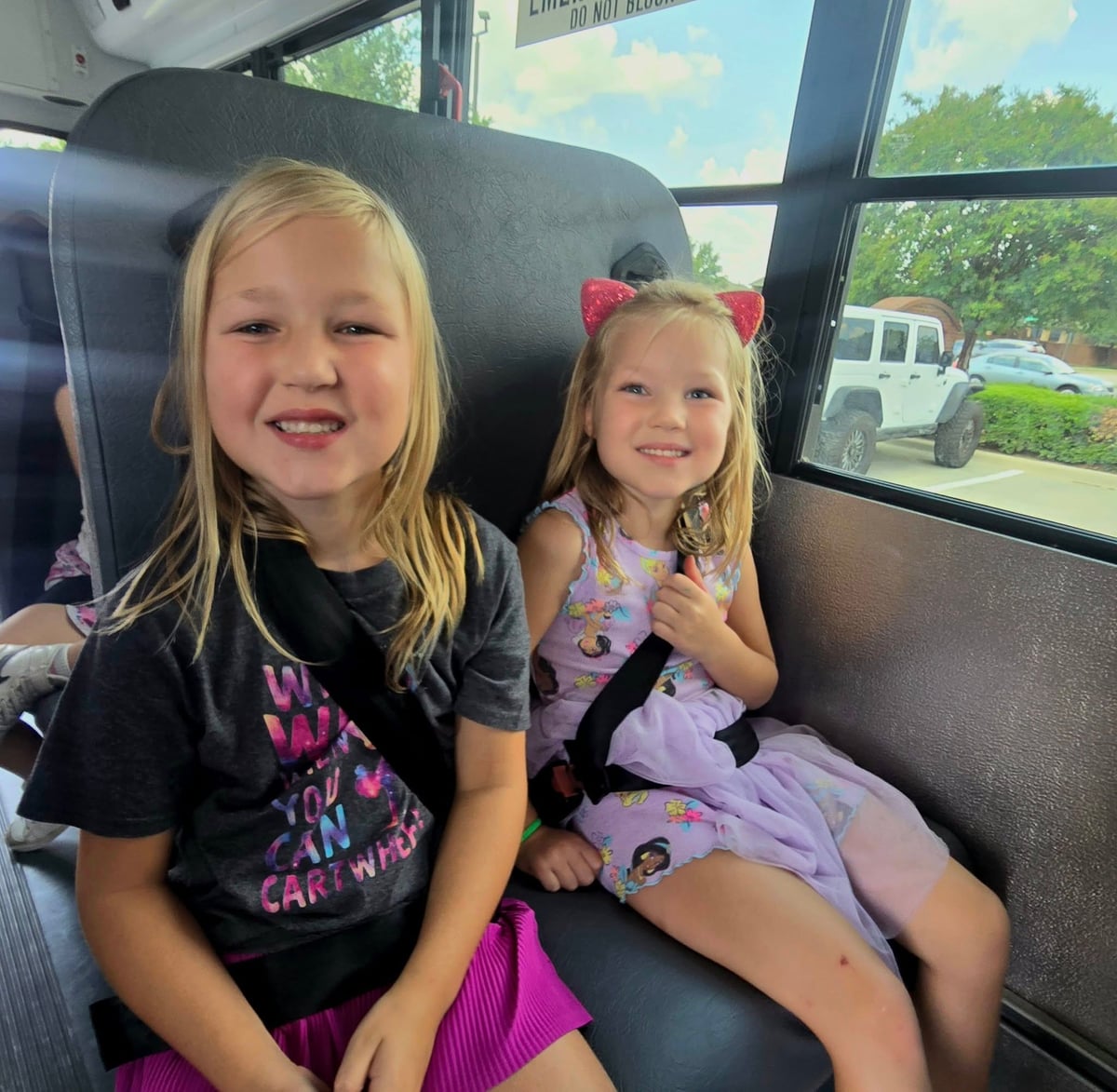 Two Primrose School Explorer students in Keller, Texas smiling and riding the school bus safely with seat belts