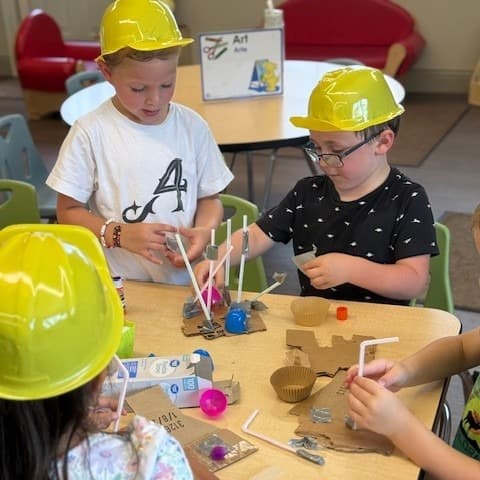 Children working together using recyclable materials to construct a house