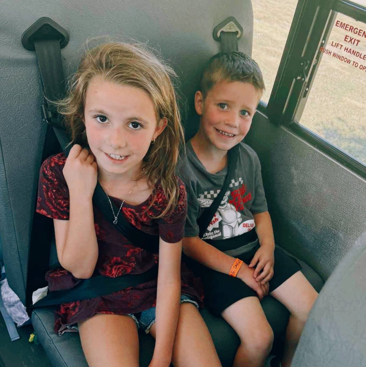 Two Primrose School Explorer students in Fort Worth, Texas smiling and riding the school bus safely with seat belts