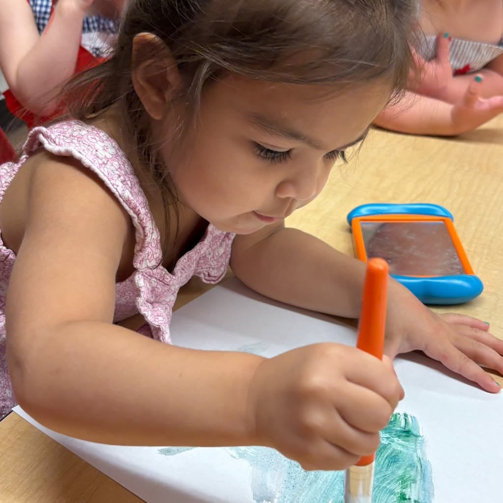 Preschooler using a paintbrush to create colorful artwork during a hands-on art activity that encourages creativity and fine motor development at Primrose School.