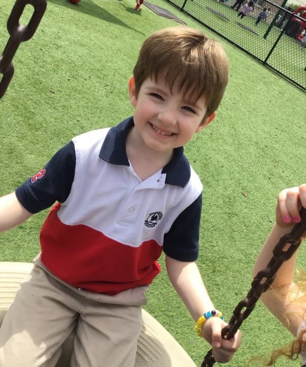 Preschool student happily swinging outdoors to enhance balance and gross motor development during playground time