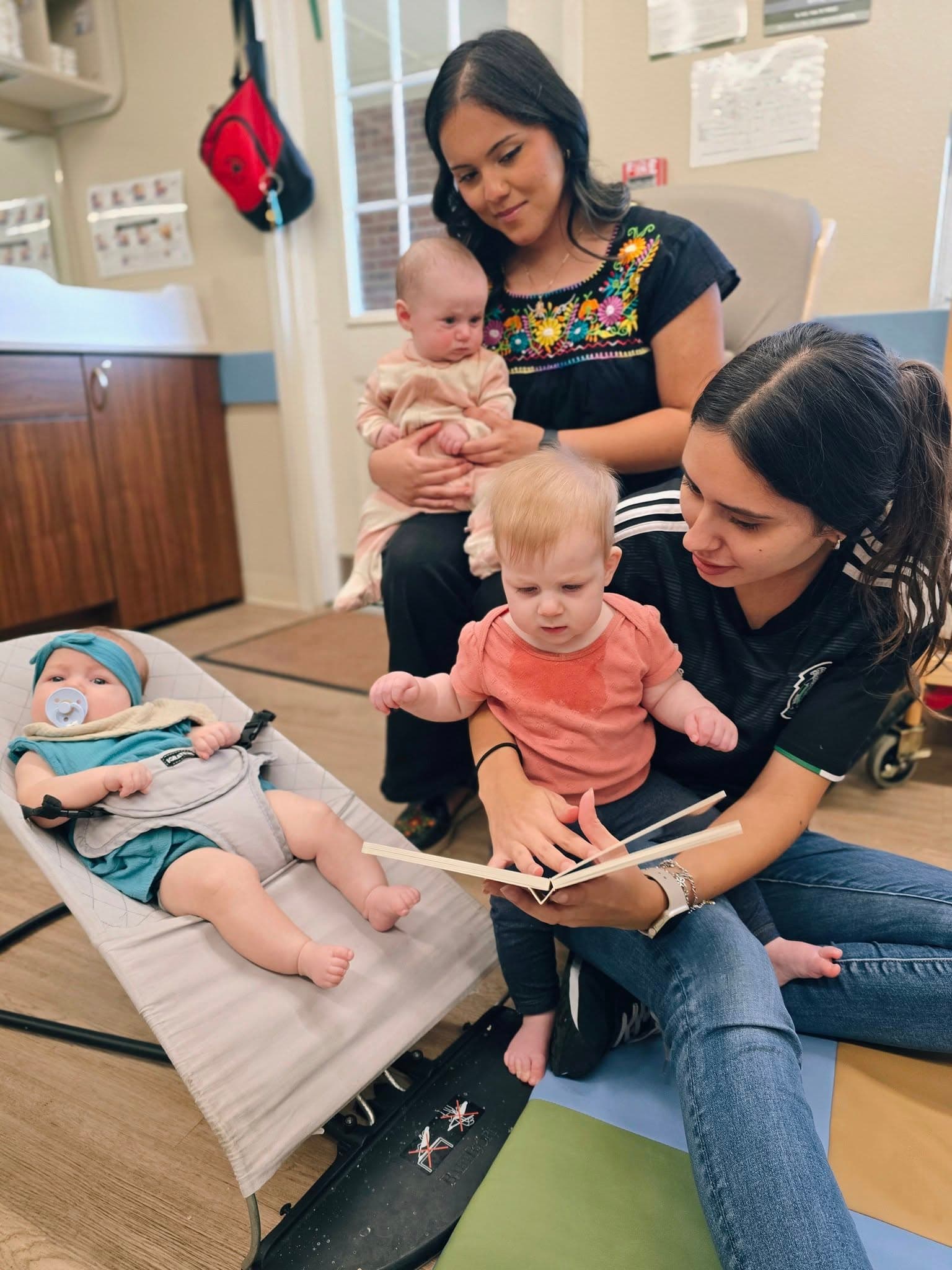 Daycare in Fort Worth 76244 teachers reading and caring for infants during interactive learning time.