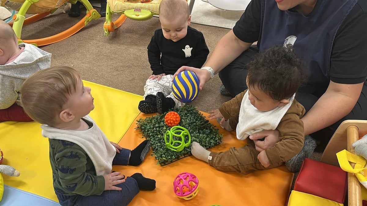 Infants gathered with a teacher during a sensory play activity, exploring textured materials and colorful toys that encourage curiosity, social interaction, and early development at Primrose School.