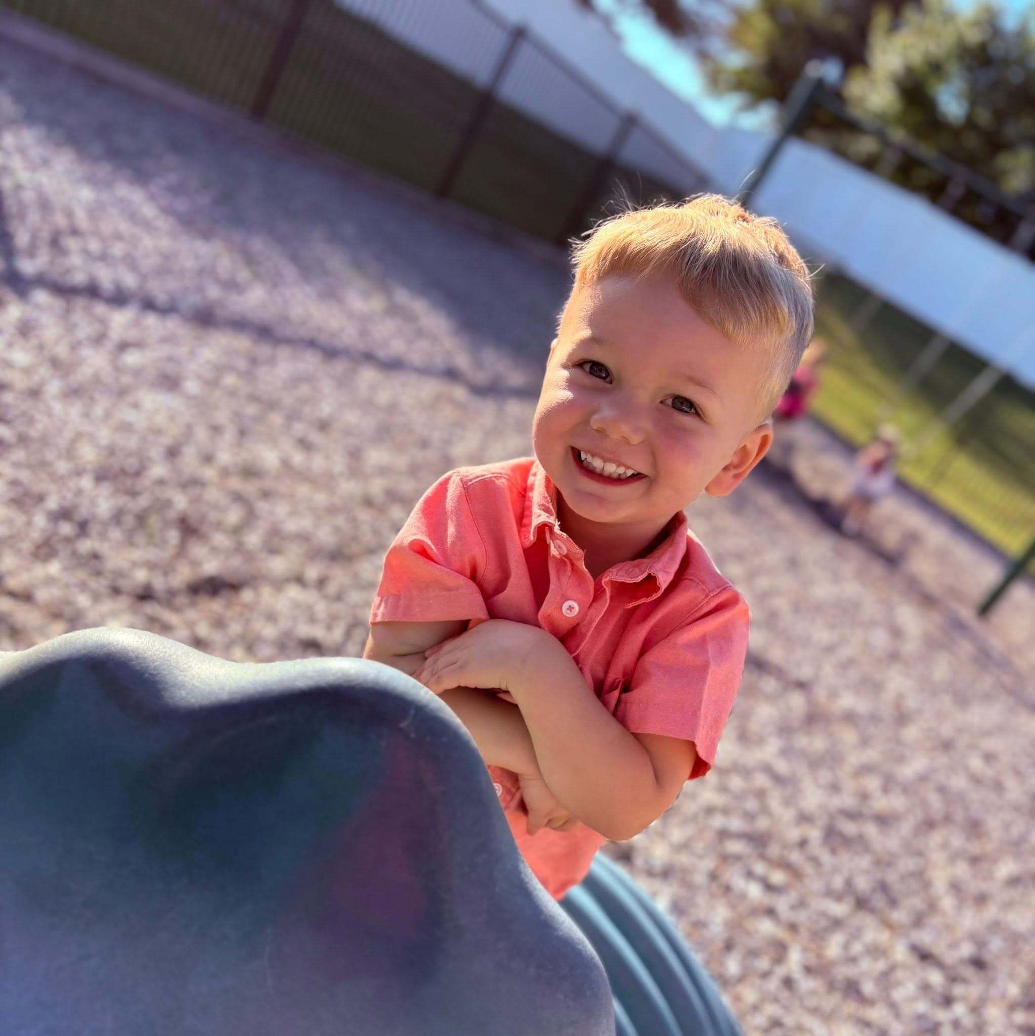 Smiling preschool child playing on playground during outdoor time at Fort Worth preschool