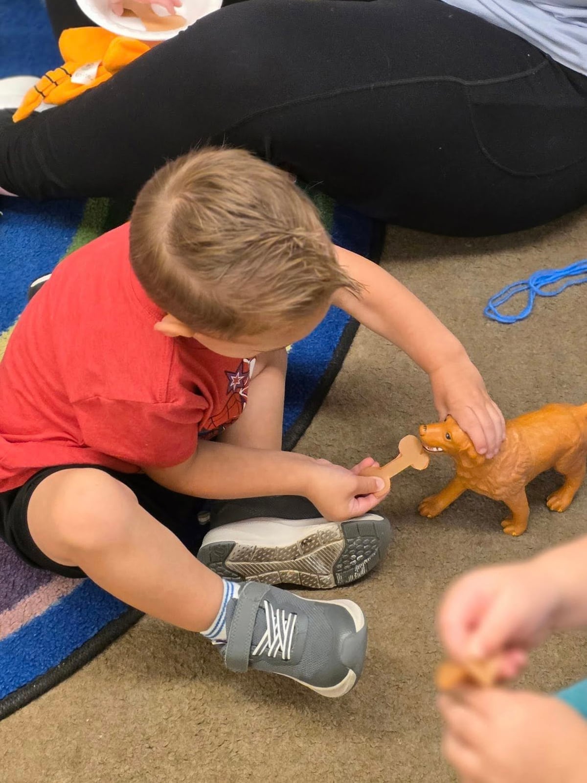 Child engaging in imaginative play by feeding a toy dog, developing empathy, creativity, and social-emotional skills.