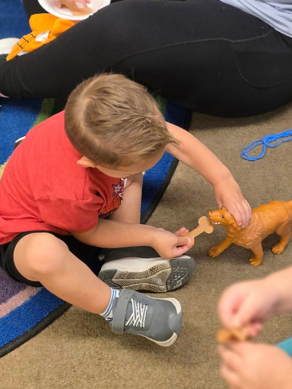 Child engaging in imaginative play by feeding a toy dog, developing empathy, creativity, and social-emotional skills.