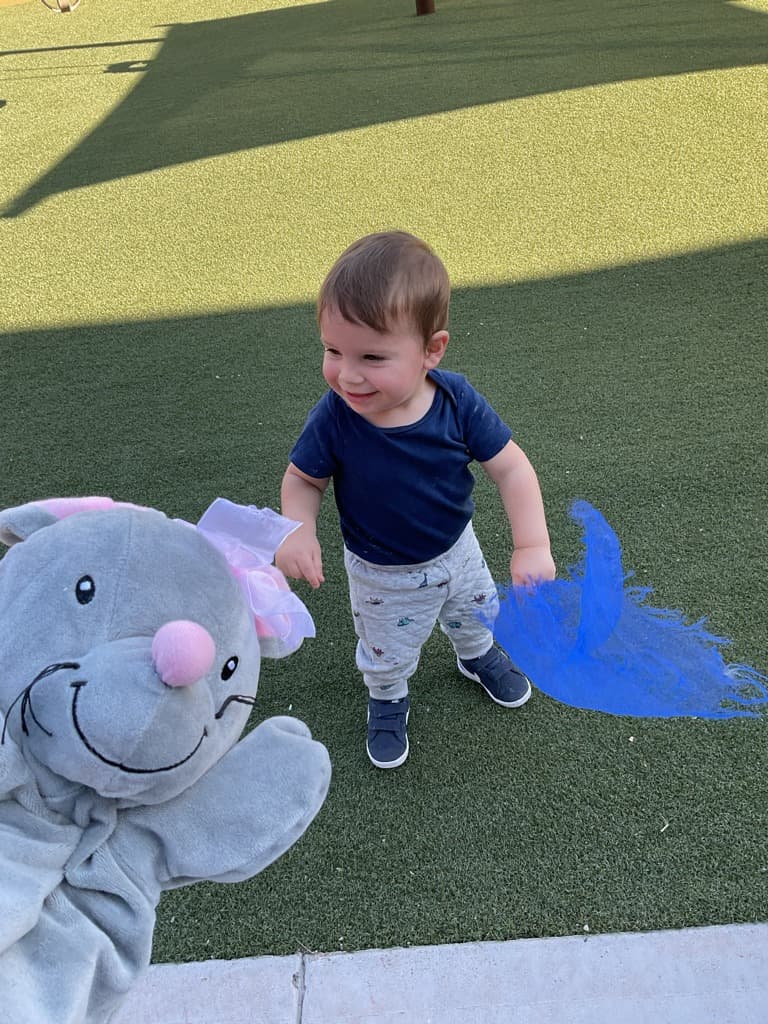 Toddler enjoying outdoor play while chasing and exploring colorful movement scarves, helping build coordination, balance, and confidence.