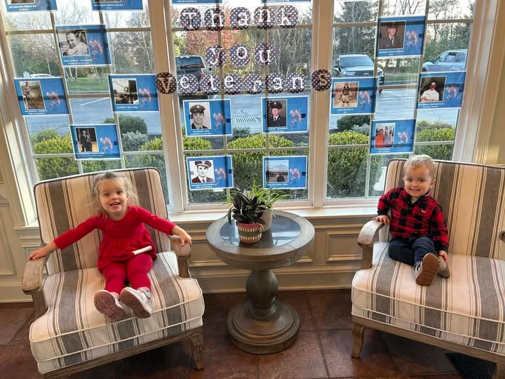 2 children sitting in chairs smiling