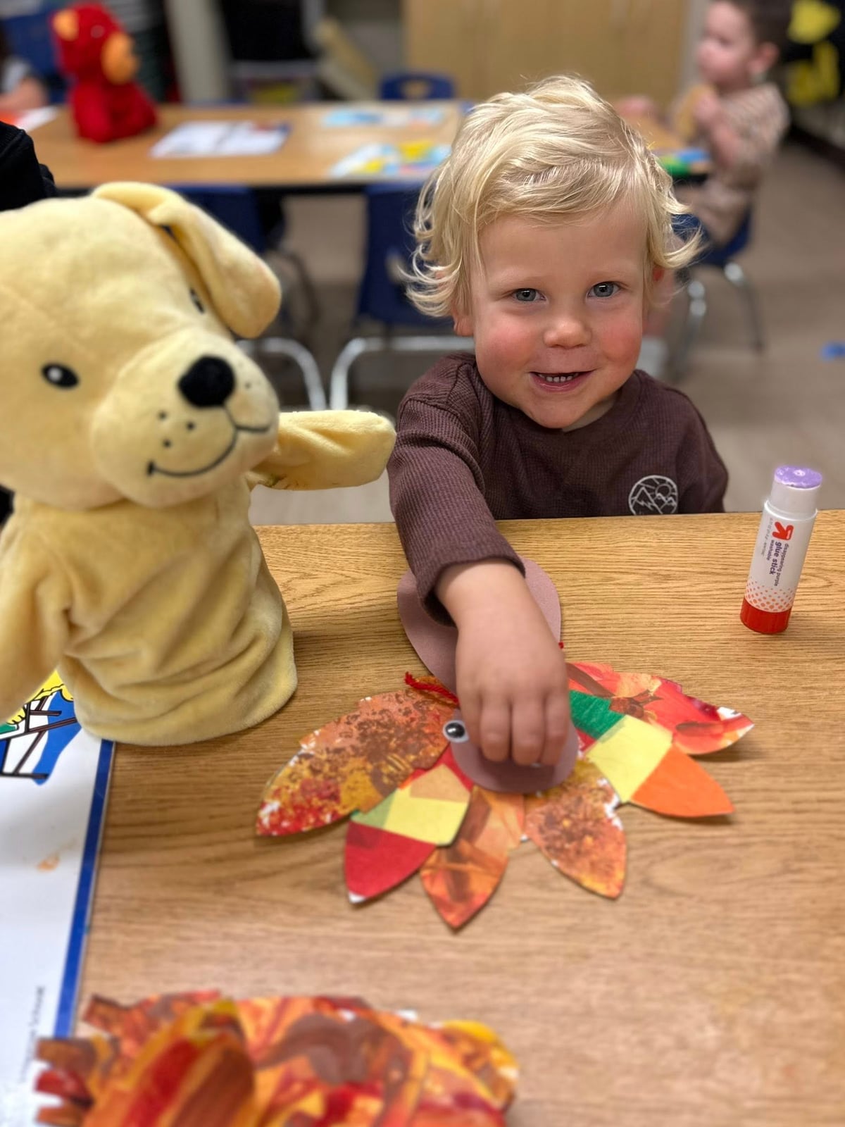 Toddler proudly creating a colorful fall-themed turkey craft while practicing fine motor skills and creative expression.