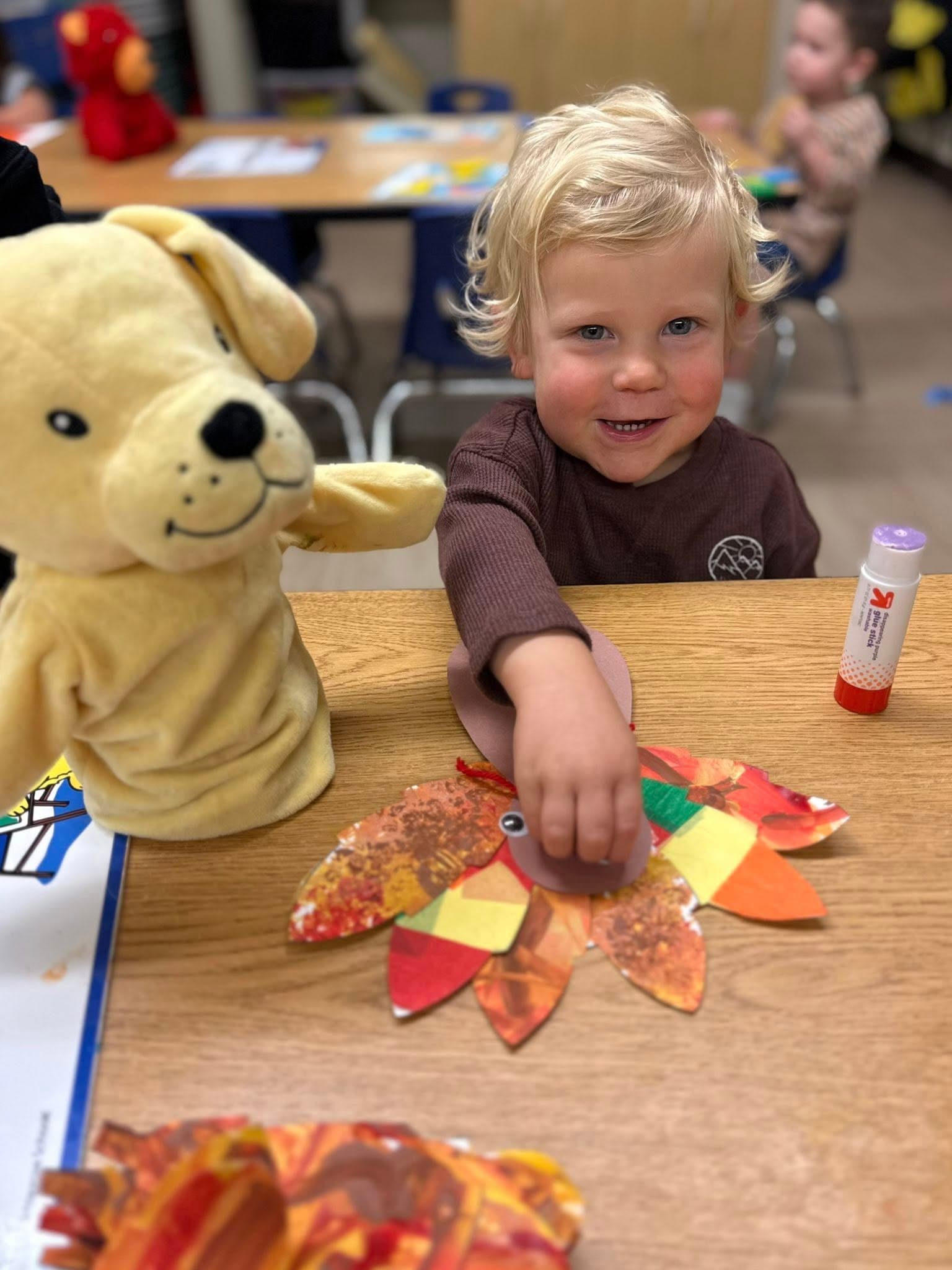 Toddler proudly creating a colorful fall-themed turkey craft while practicing fine motor skills and creative expression.