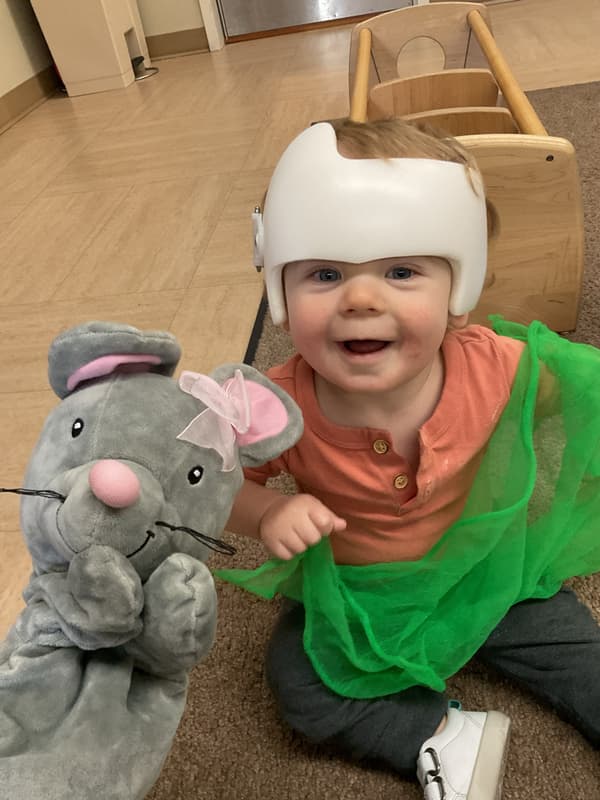 Smiling toddler exploring colorful sensory scarves and imaginative play materials while developing curiosity and sensory awareness in the classroom.