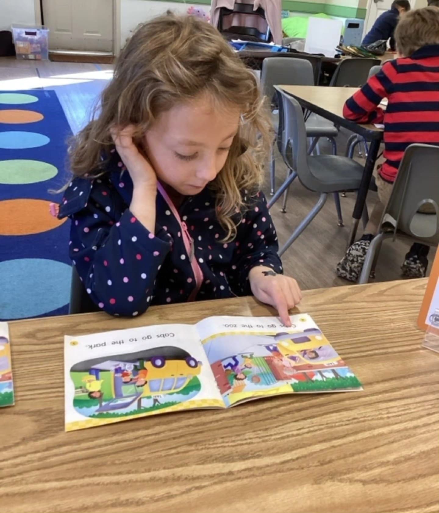 A girl sitting at a table reading a book