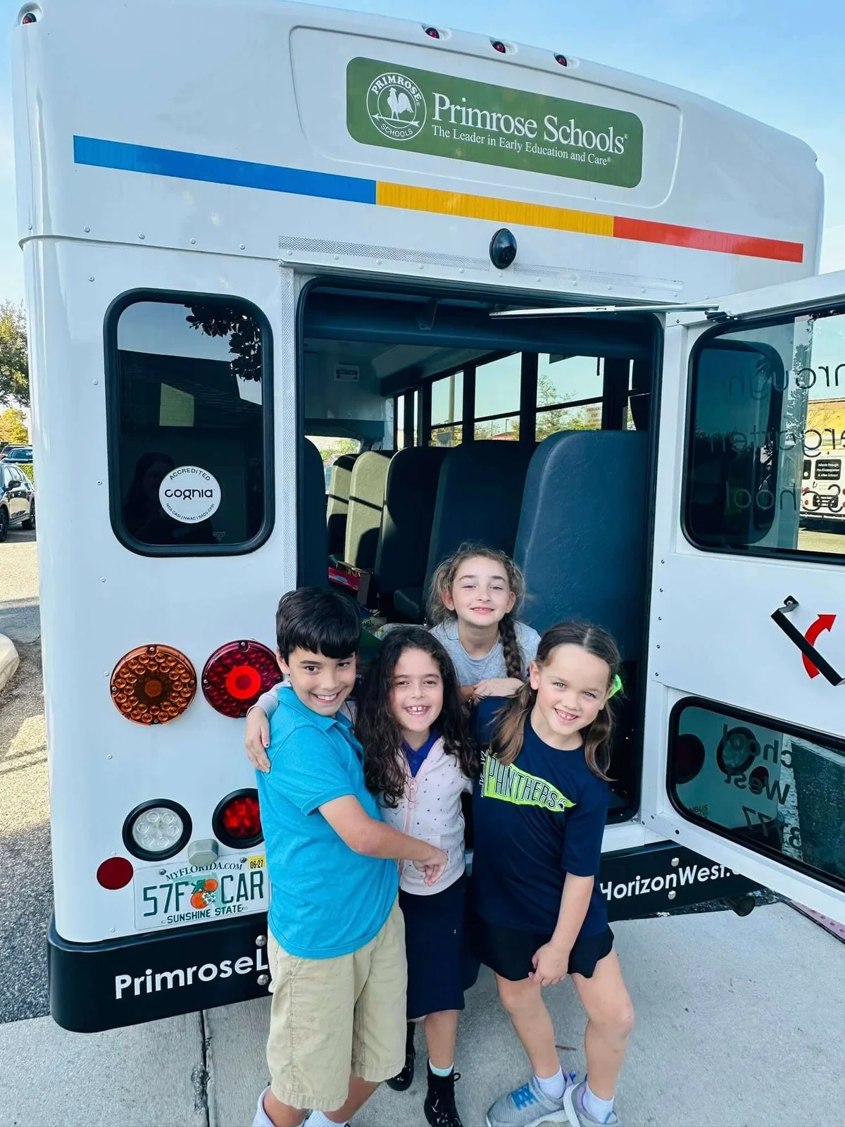 a boy and three girls standing behind a bus