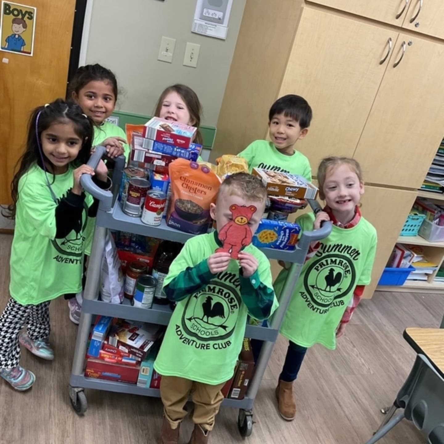 5 children standing with a cart full of food items to be donated