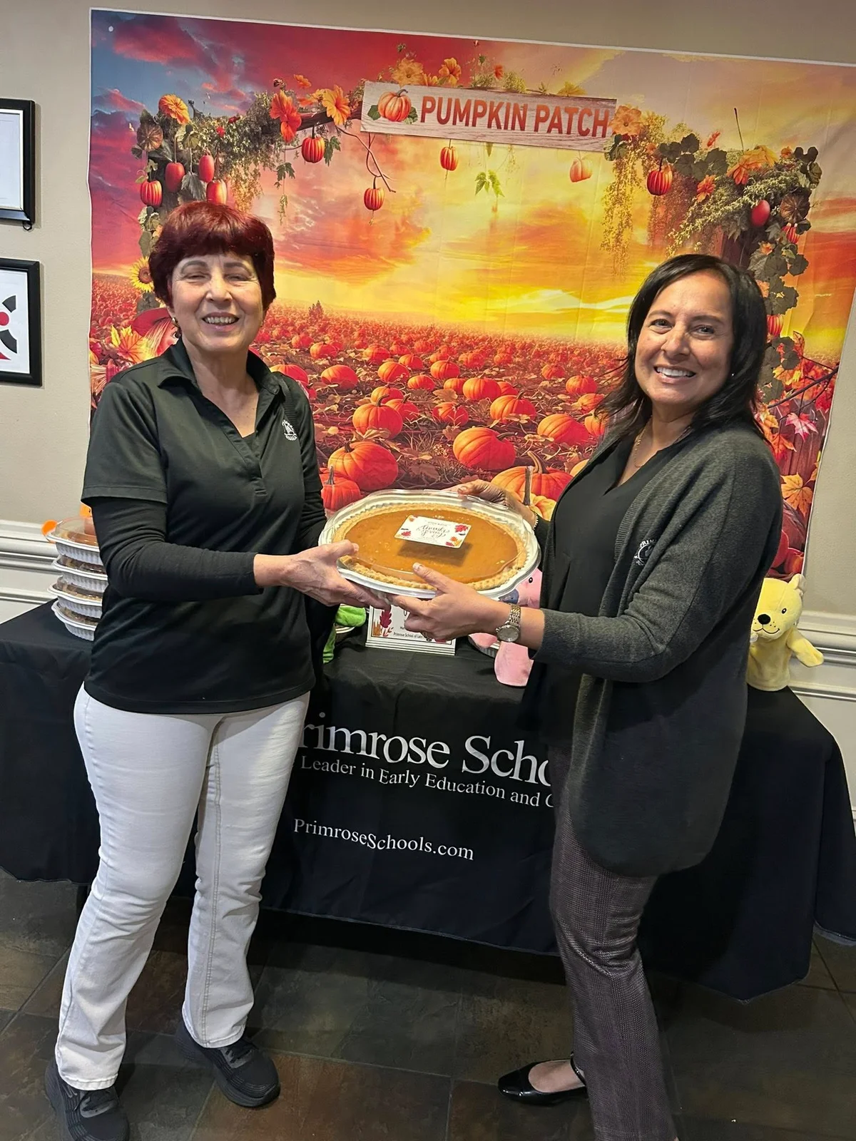two women holding a pumpkin pie