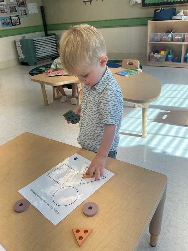 Boy matching shapes to the same shape on the paper