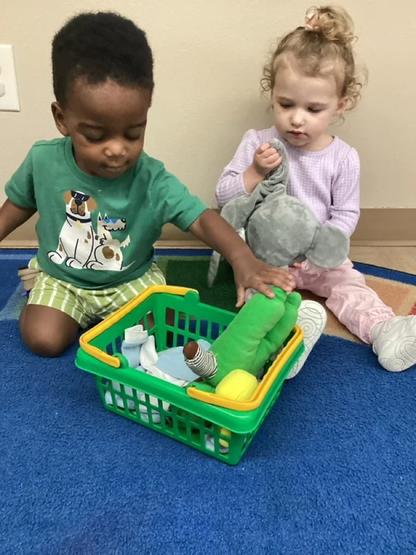 boy and girl on a blue carpet exploring objects