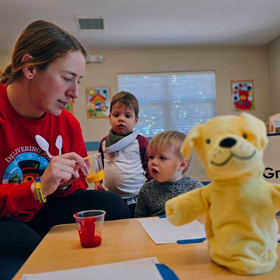 Teacher helping a child during a small group art project, guiding creativity and fine motor skills in an early learning classroom located in Fort Worth, TX.