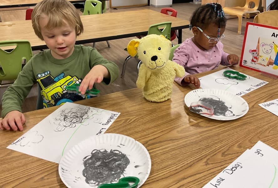 Boy and girl painting with a yellow dog puppet watching over