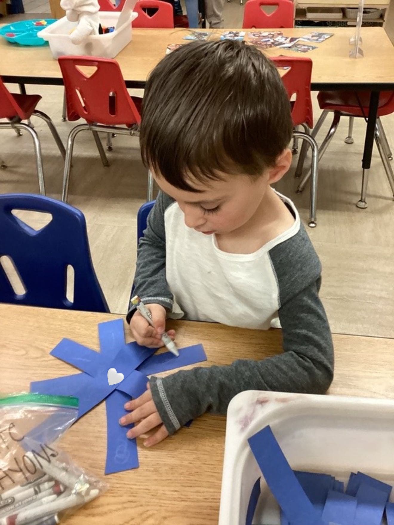 Child decorating a paper snowflake craft while practicing creativity and fine motor skills.