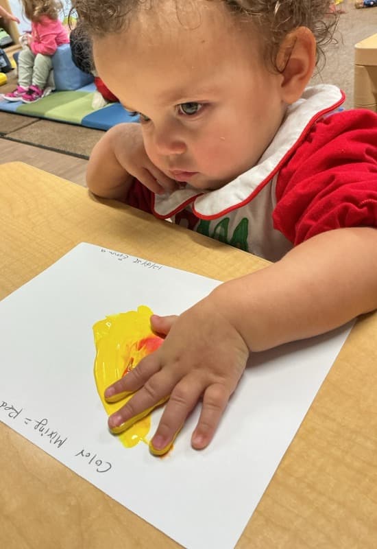 girl mixing yellow and red paint to make orange paint