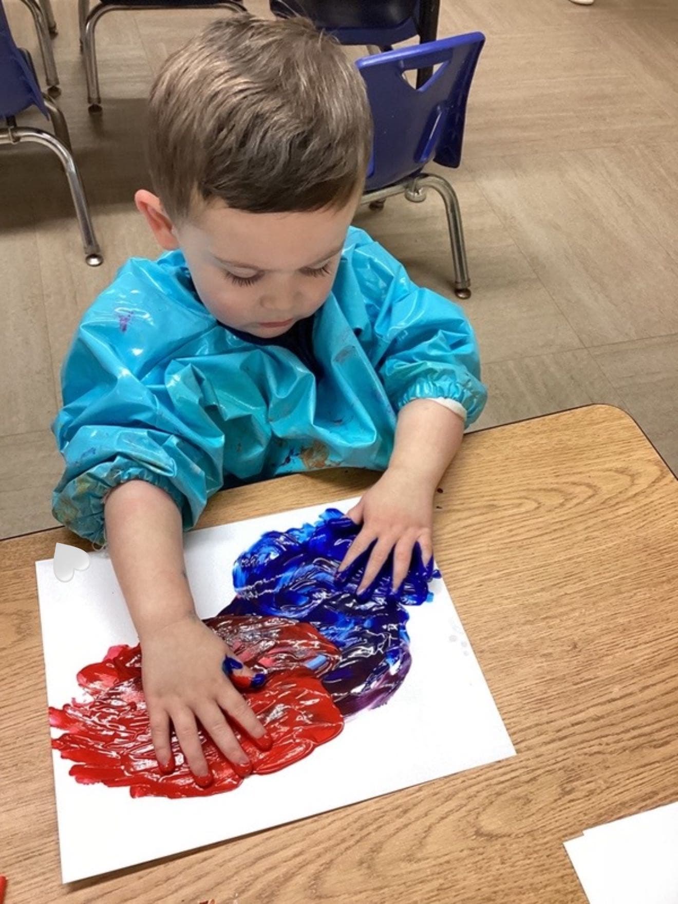 Child exploring red and blue paint with their hands during a sensory art activity that encourages creativity and color discovery.
