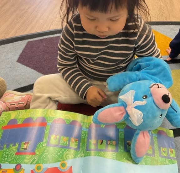 Toddler exploring a colorful activity mat alongside Ally® the Bunny, encouraging curiosity, cognitive development, and independent learning.