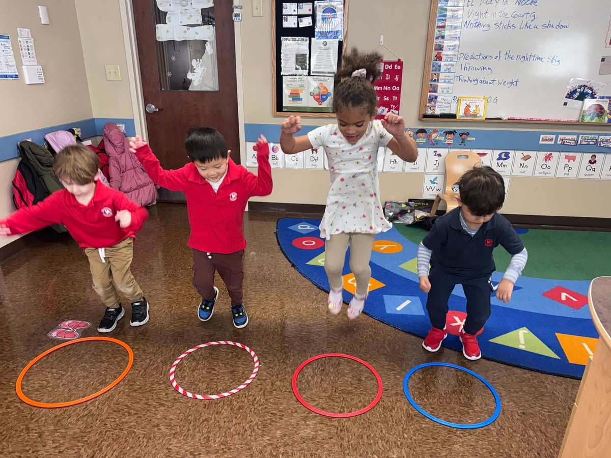 Preschool children jumping into colorful hoops during a movement activity that builds balance, coordination, listening skills, and gross motor development at Primrose School.