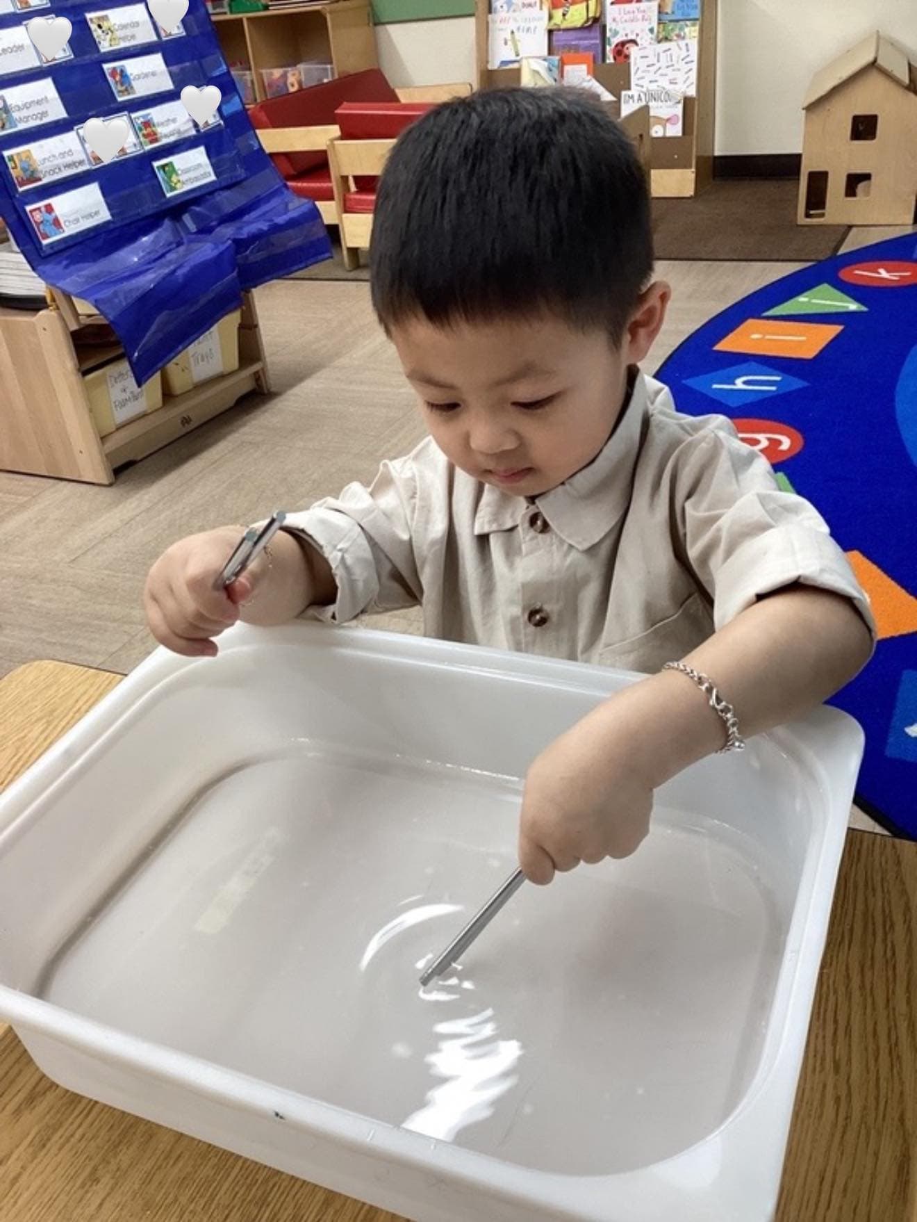 Young learner using magnetic tools to explore science concepts through a water-based investigation activity.
