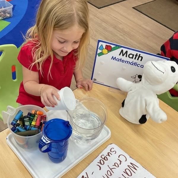 Preschool student exploring measurement concepts by pouring water during a hands-on math activity that builds counting, comparison, and problem-solving skills.