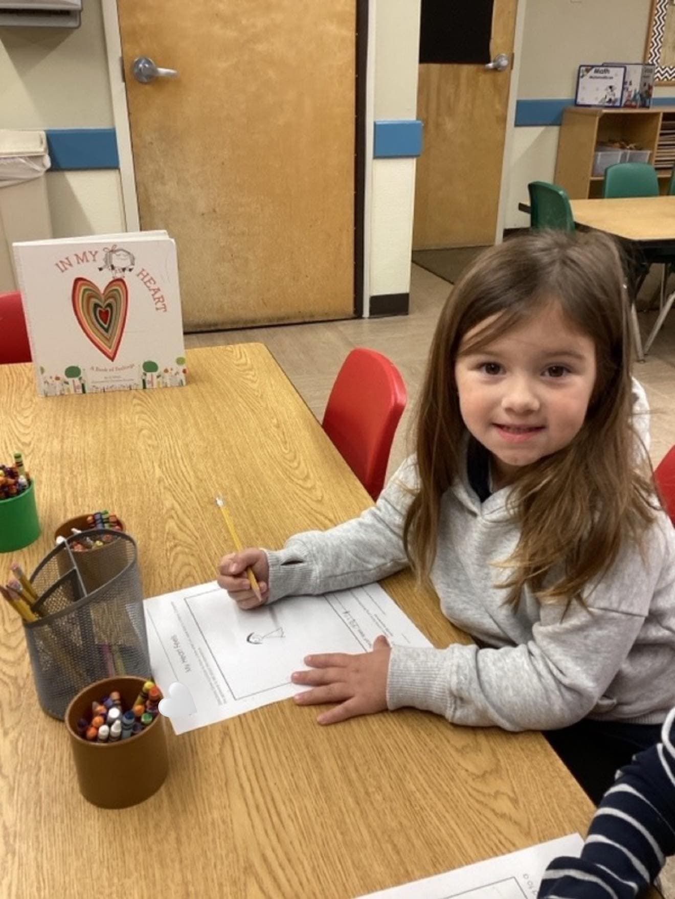 Young student working on a writing and drawing activity inspired by a classroom book about kindness and emotions.