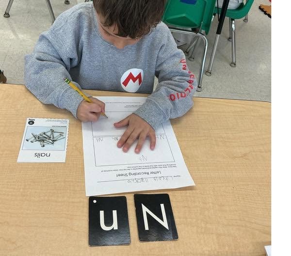 Preschool student practicing letter recognition and handwriting by identifying and writing the letter N during a literacy activity at Primrose School.