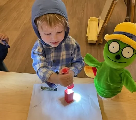 Preschooler using a flashlight to explore light and shadows during a hands-on STEM activity that promotes curiosity, observation, and problem-solving skills.