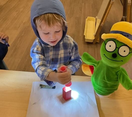 Preschooler using a flashlight to explore light and shadows during a hands-on STEM activity that promotes curiosity, observation, and problem-solving skills.