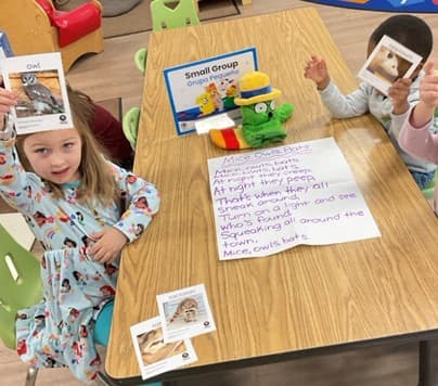 2 girls and 1 boy holding up photos during small group activity