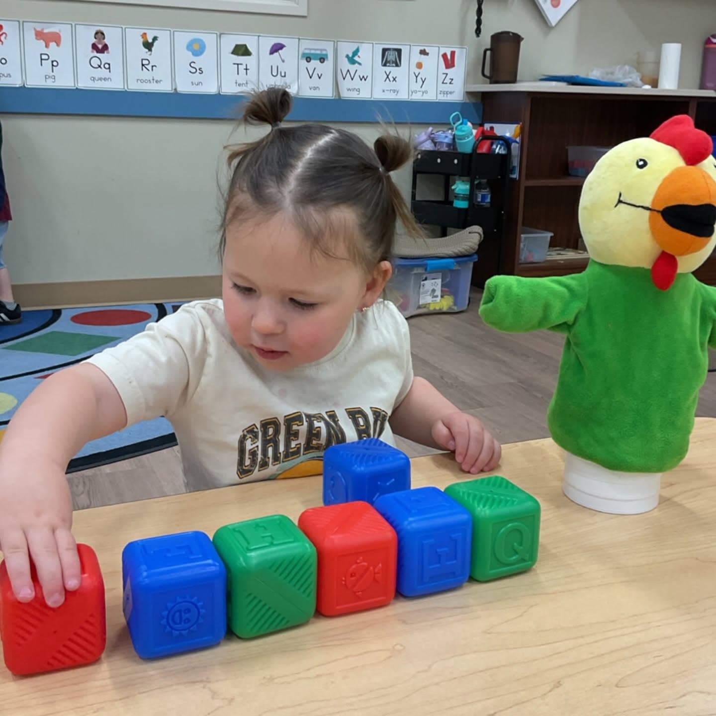 Toddler arranging colorful blocks in a sequence while developing early math concepts, spatial awareness, and critical thinking skills.