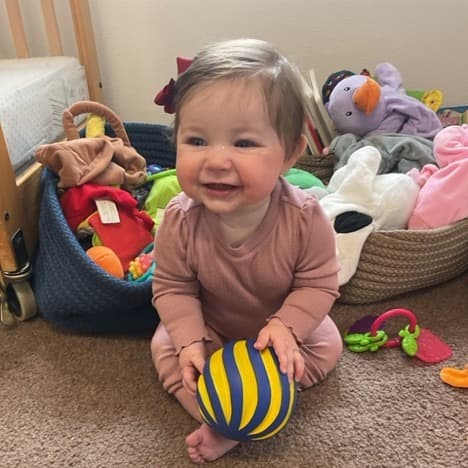 Infant smiling with a ball