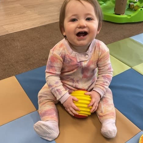 Infant laughing with a ball