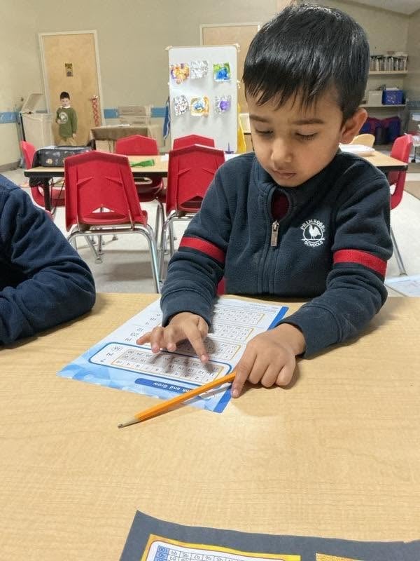 Preschool student practicing number recognition and counting during an engaging math activity that builds early numeracy skills at Primrose School.