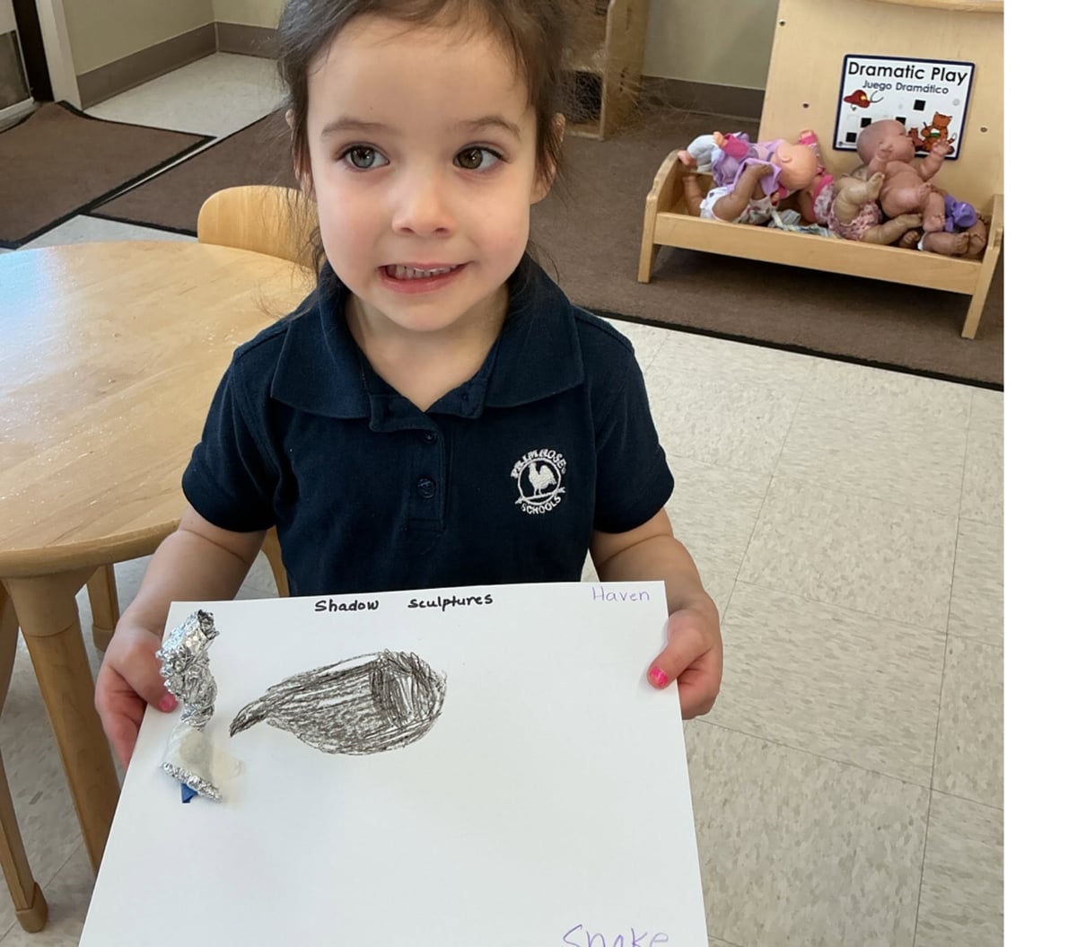 Preschool student proudly displaying a shadow sculpture art project that combines creativity, observation, and early science concepts at Primrose School.