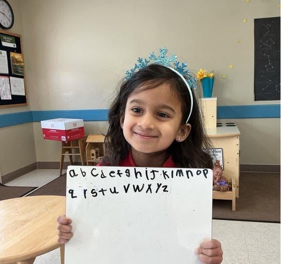 Pre-K student proudly displaying handwritten uppercase and lowercase alphabet letters while building early literacy and handwriting skills at Primrose School.