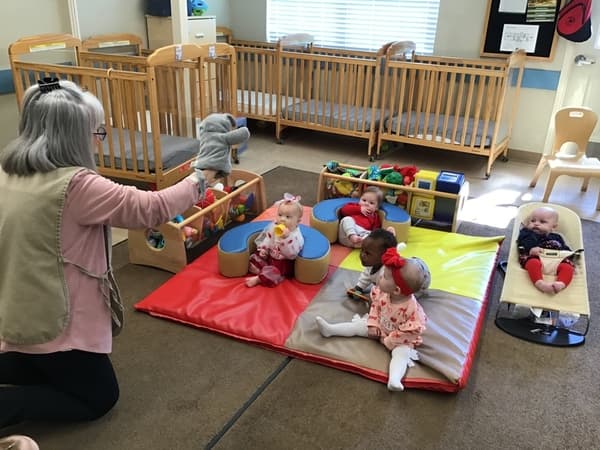 Teacher holding mouse puppet reading to the classroom