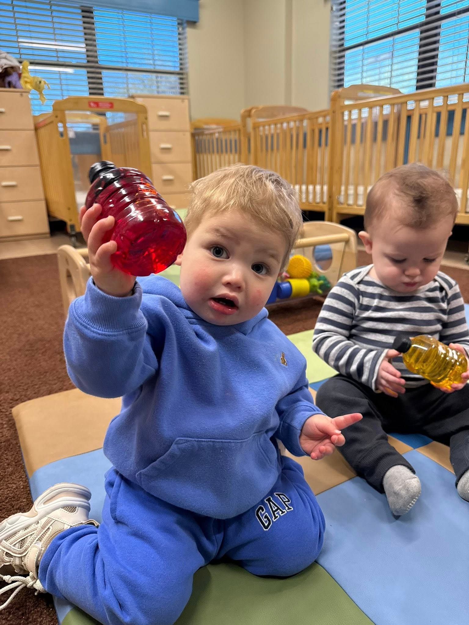 Toddlers examining colorful sensory bottles while developing curiosity, visual tracking, and fine motor skills.