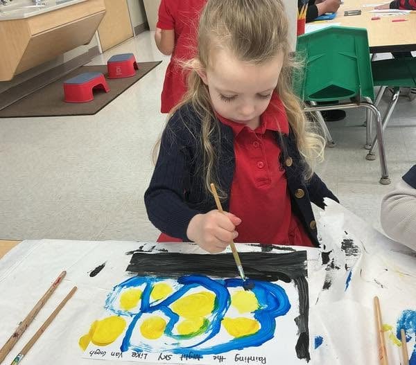 Preschooler carefully painting a vibrant artwork during a classroom art activity that encourages creativity, fine motor development, and self-expression at Primrose School.