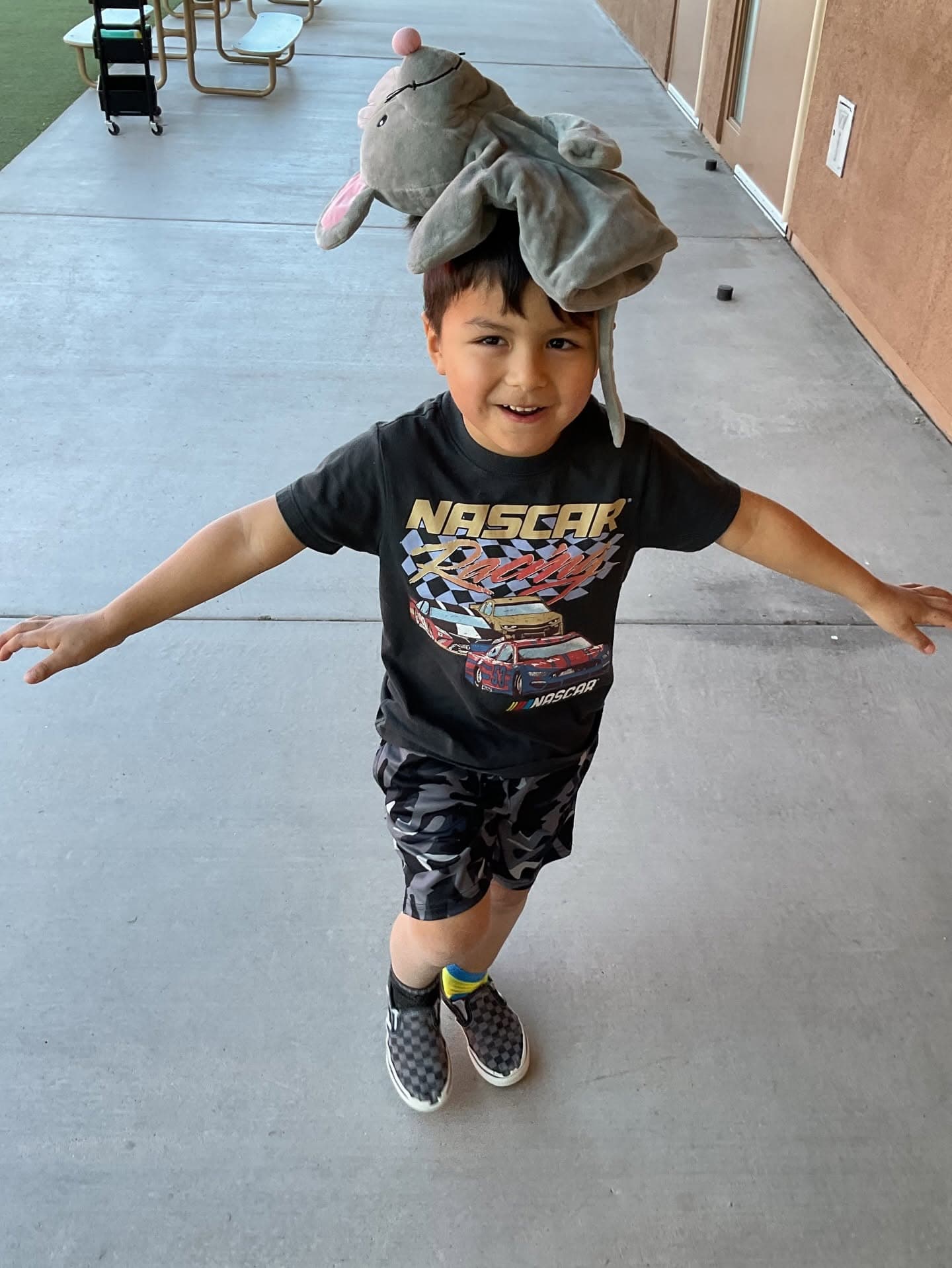 Preschool child balancing a classroom puppet on their head while engaging in imaginative play that promotes creativity, confidence, and social development.