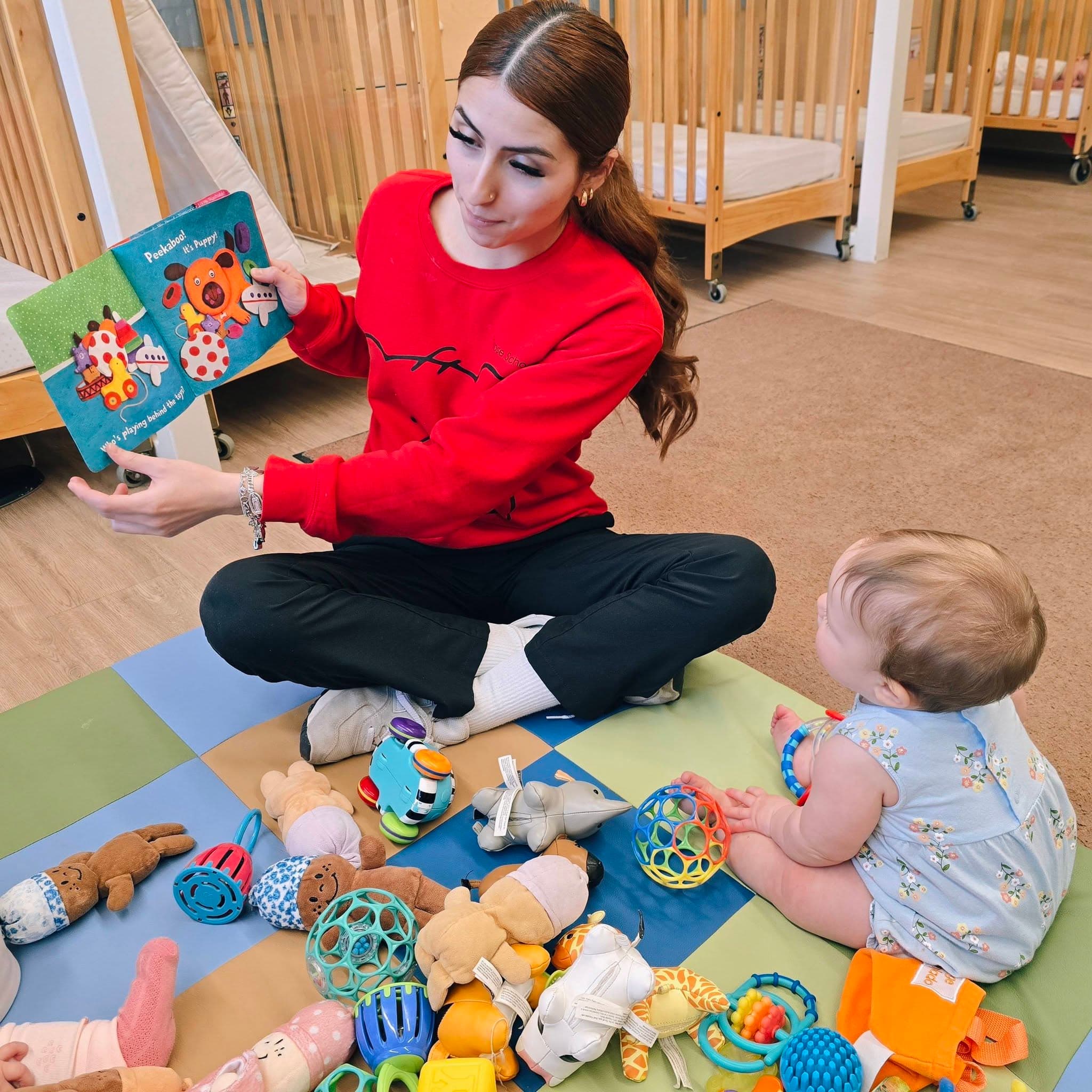 Infant teacher at Primrose School at Heritage reading a story to a baby during storytime in the classroom in Keller, Texas.