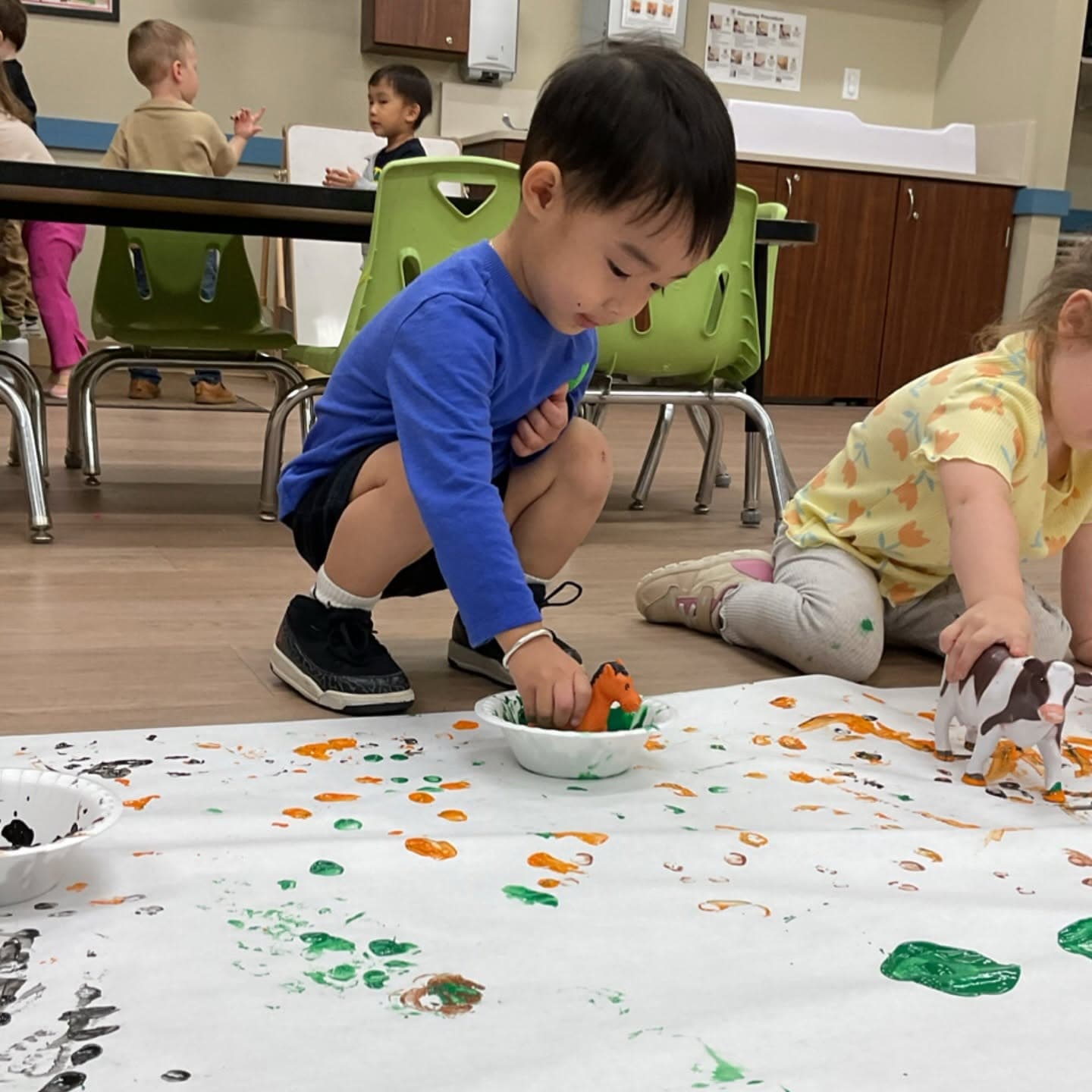 Preschool children using toy farm animals to make colorful paint prints, combining imaginative play with art, sensory learning, and creative exploration.